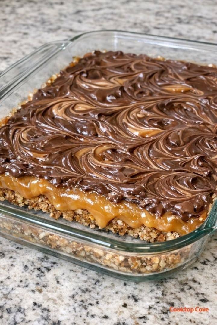 Chocolate caramel pretzel bars with swirled chocolate topping in a glass baking dish