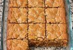 Golden pineapple coconut bars with a crackly top, cut in a glass baking dish