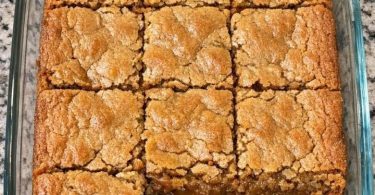 Golden pineapple coconut bars with a crackly top, cut in a glass baking dish