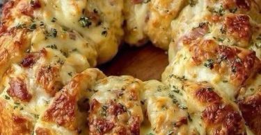 Cheesy ham bread ring baked golden brown, topped with melted cheese and herbs