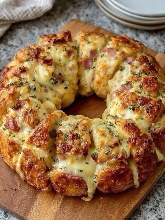 Cheesy ham bread ring baked golden brown, topped with melted cheese and herbs