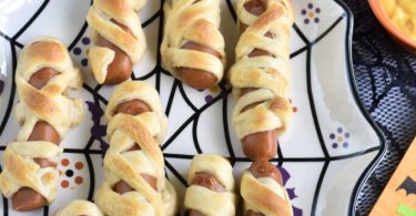 Hot Dog Mummies wrapped in crescent dough on a Halloween plate