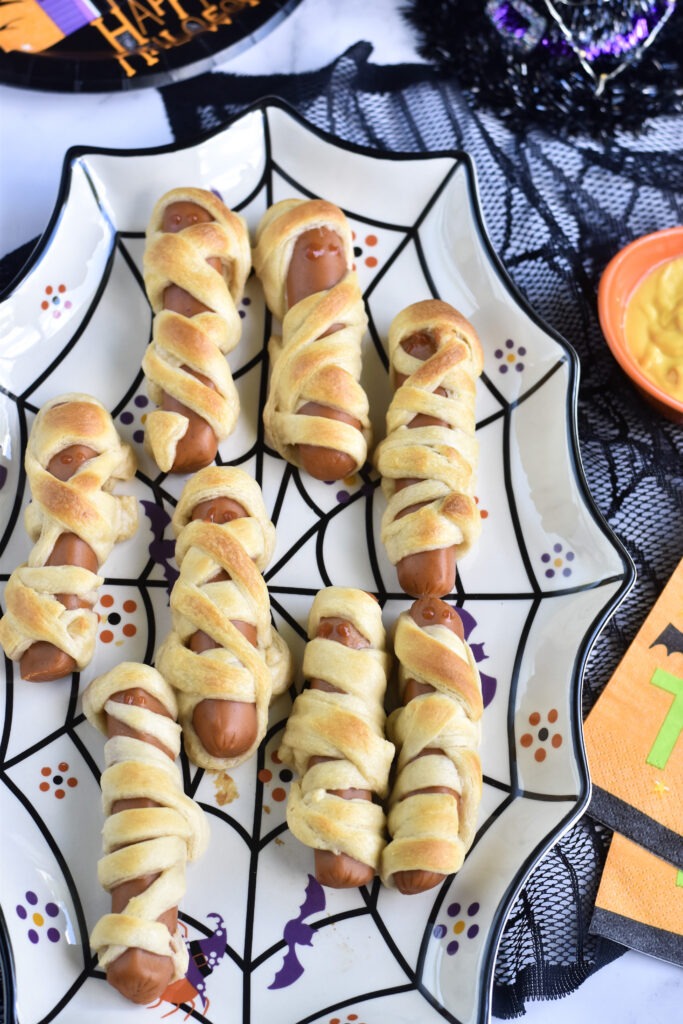 Hot Dog Mummies wrapped in crescent dough on a Halloween plate